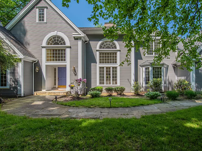 Front entrance of a grand Colonial home in Farmington, CT, with pristine landscaping and large arched windows.