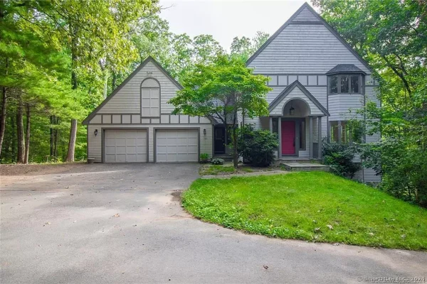 Exterior view of a modern home surrounded by trees with a red front door.