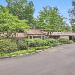 Exterior view of a contemporary home surrounded by lush greenery with a circular driveway.
