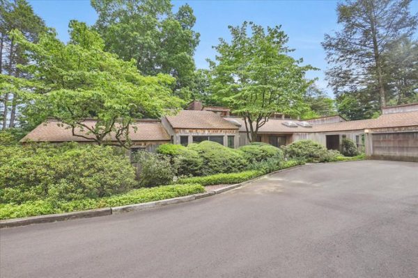 Exterior view of a contemporary home surrounded by lush greenery with a circular driveway.