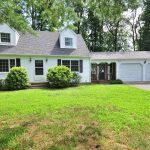 A white Cape Cod-style house at 1 Burlington Road, Unionville, CT 06085, with a well-maintained lawn, black shutters, and a two-car garage surrounded by trees.