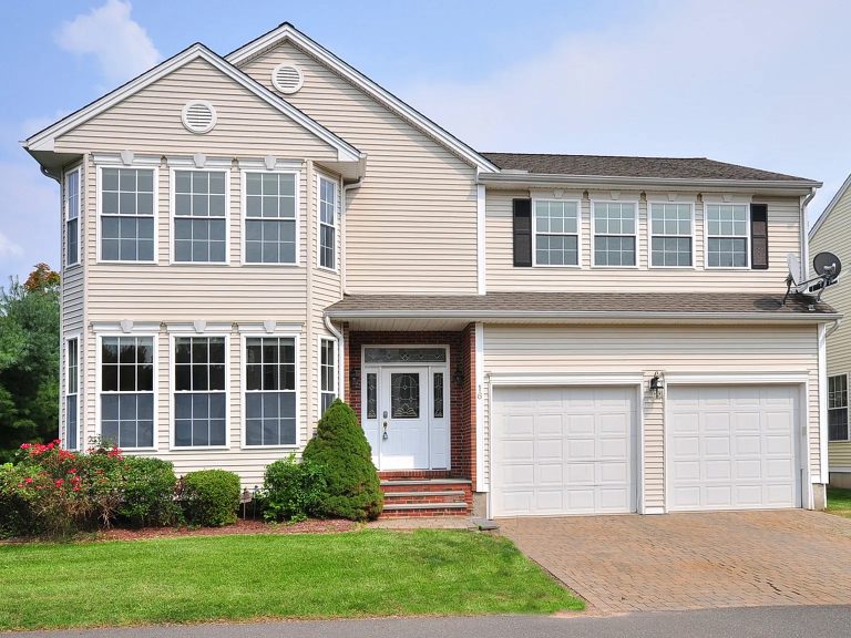 Front view of the two-story Colonial-style home at 16 Cobble Ct, Unionville, CT 06085, featuring a double garage and well-maintained landscaping.