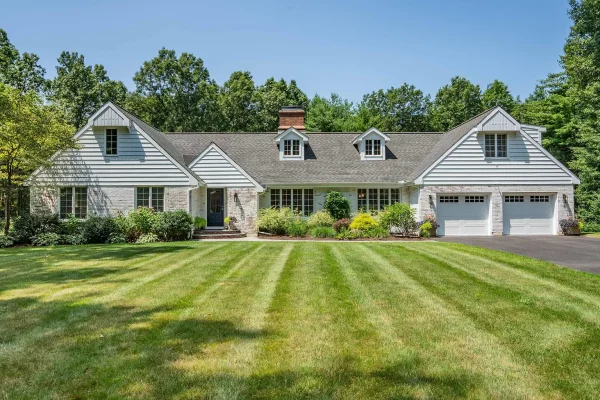 Front view of a beautifully landscaped white ranch-style home with a well-maintained lawn and attached garage in Farmington, CT