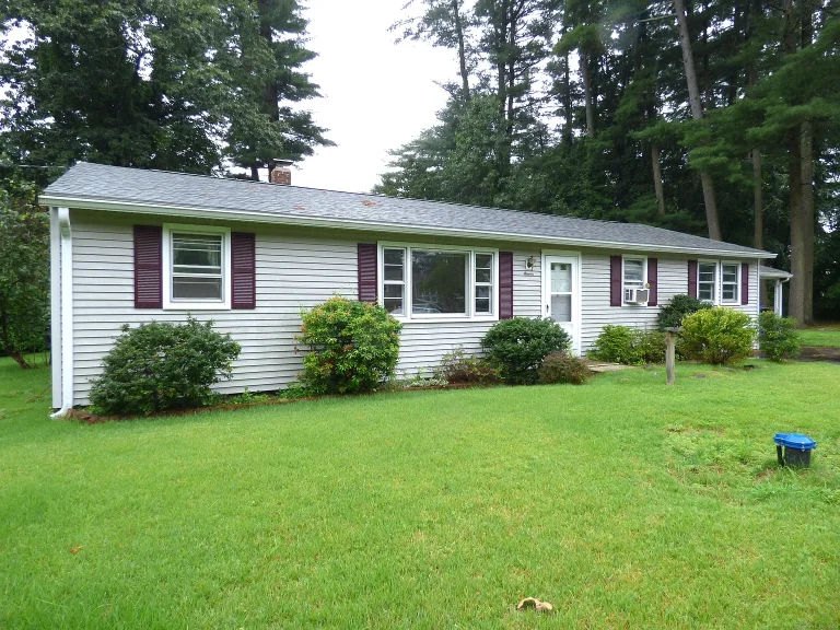 Single-story ranch-style home with gray vinyl siding and burgundy shutters in Farmington, CT, surrounded by lush green grass and mature trees.