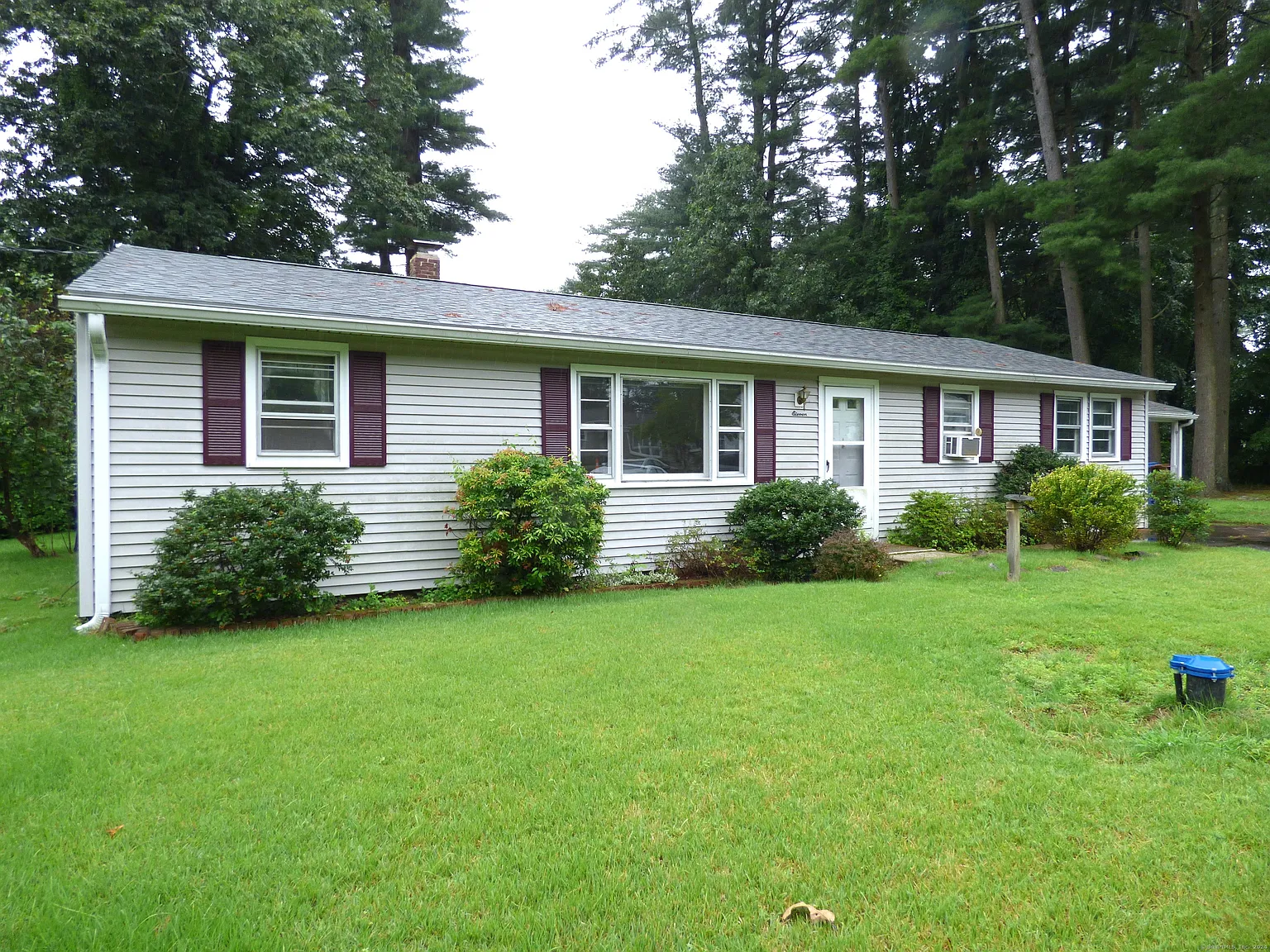 Single-story ranch-style home with gray vinyl siding and burgundy shutters in Farmington, CT, surrounded by lush green grass and mature trees.