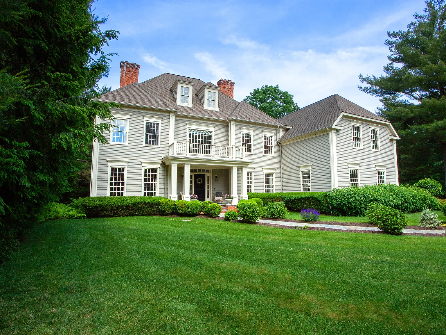 Front exterior view of the luxurious colonial-style home at 7 Wentworth Park, Farmington, CT 06032, featuring a manicured lawn, professional landscaping, and a grand entrance.