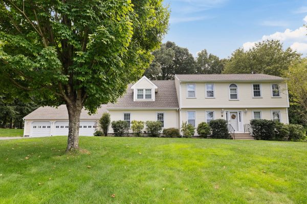 Front view of a large colonial-style house with a three-car garage and well-maintained lawn at 9 Juniper Lane, Farmington, CT.