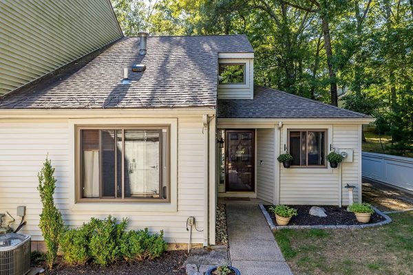 Front view of a cozy, two-story townhouse with light siding at 125 Farmington Chase Cres #125, Farmington, CT 06032, featuring a small garden and entryway.