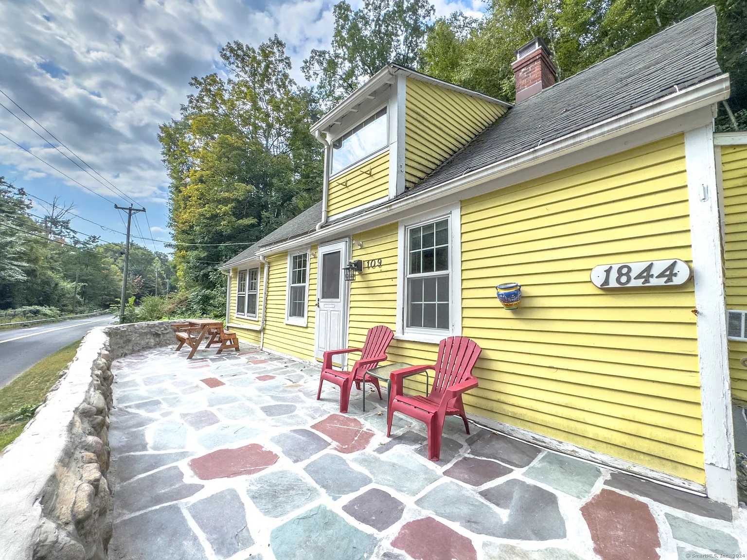 Interior of the historic colonial home at 109 River Rd, Unionville, CT, featuring rustic wood beams and bright yellow exterior.