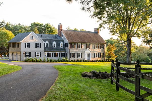 Front exterior of the Colonial estate at 325 Old Mountain Rd, Farmington, CT 06032, with a long driveway and expansive green lawns surrounded by trees.