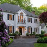 Elegant Georgian Colonial-style home at 11 Salisbury Way, Farmington, CT, featuring white clapboard siding, black shutters, and manicured landscaping with vibrant greenery and purple flowering shrubs.