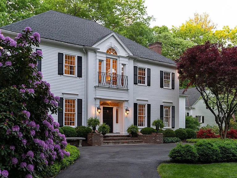 Elegant Georgian Colonial-style home at 11 Salisbury Way, Farmington, CT, featuring white clapboard siding, black shutters, and manicured landscaping with vibrant greenery and purple flowering shrubs.