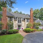 Exterior view of a luxury colonial-style home at 4 Pembroke Hill, Farmington, CT, featuring brick chimneys, manicured landscaping, and a three-car garage.