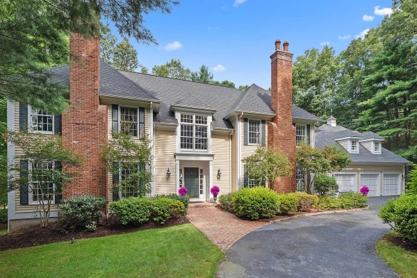 Exterior view of a luxury colonial-style home at 4 Pembroke Hill, Farmington, CT, featuring brick chimneys, manicured landscaping, and a three-car garage.