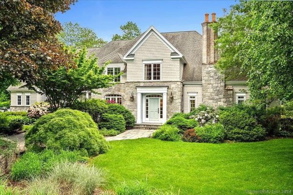 Beautiful front view of a colonial-style home located at 8 Dunham Ln, Farmington, CT, showcasing a well-manicured lawn, lush greenery, and a stone-clad entrance.